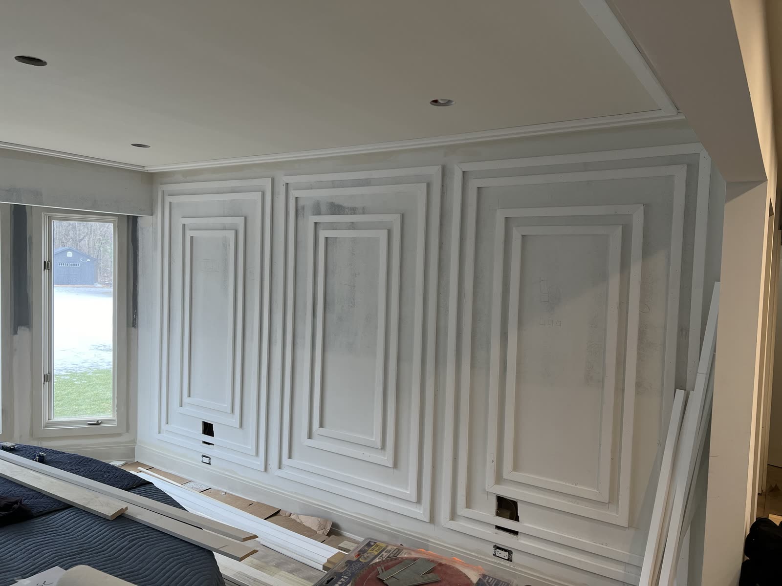 Bedroom wall before paint with three bays of molding, each three frames deep, pencil layout marks on the drywall.