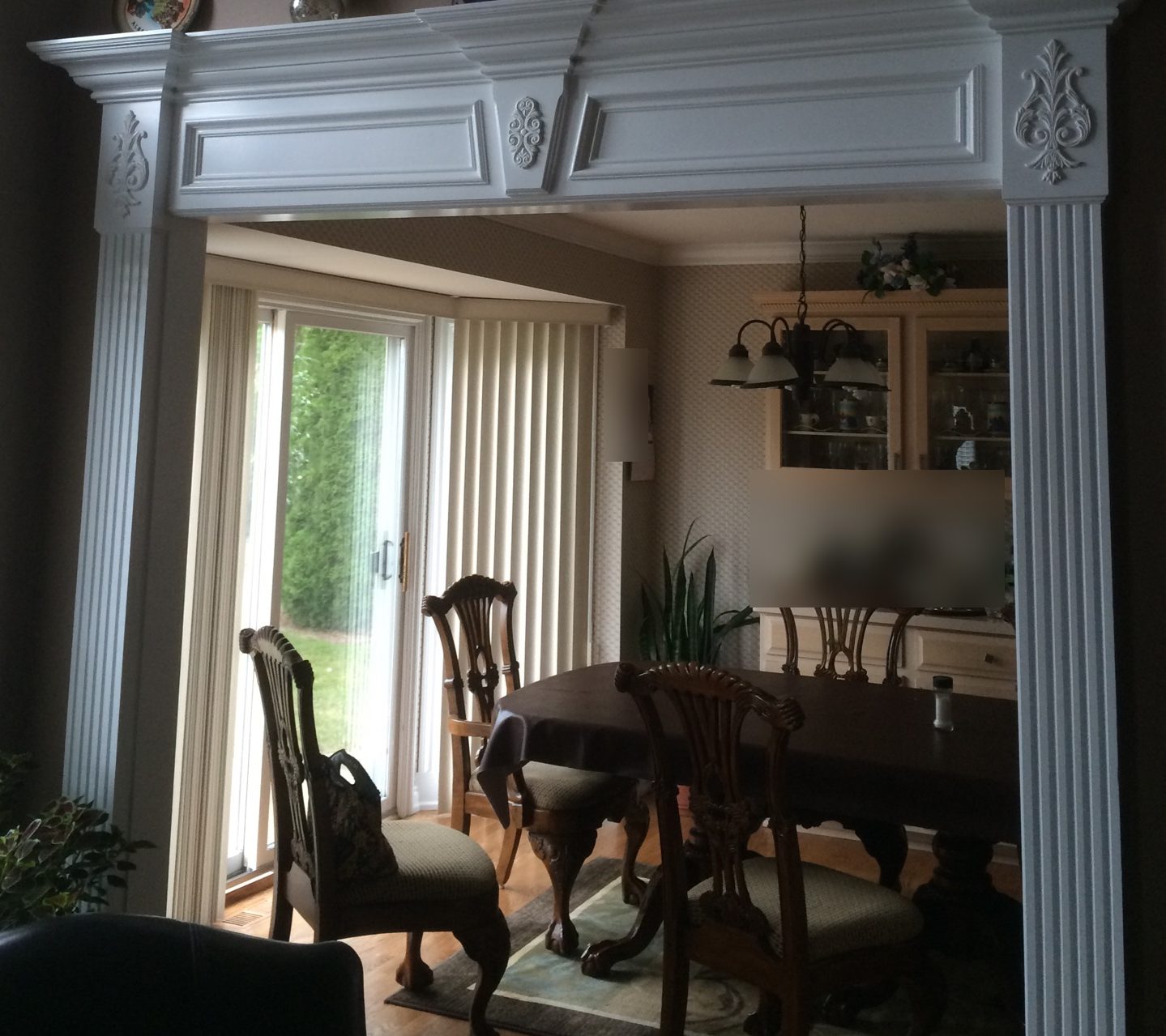Wide painted opening into a dining room: fluted pilasters with carved appliques and a paneled header under crown.