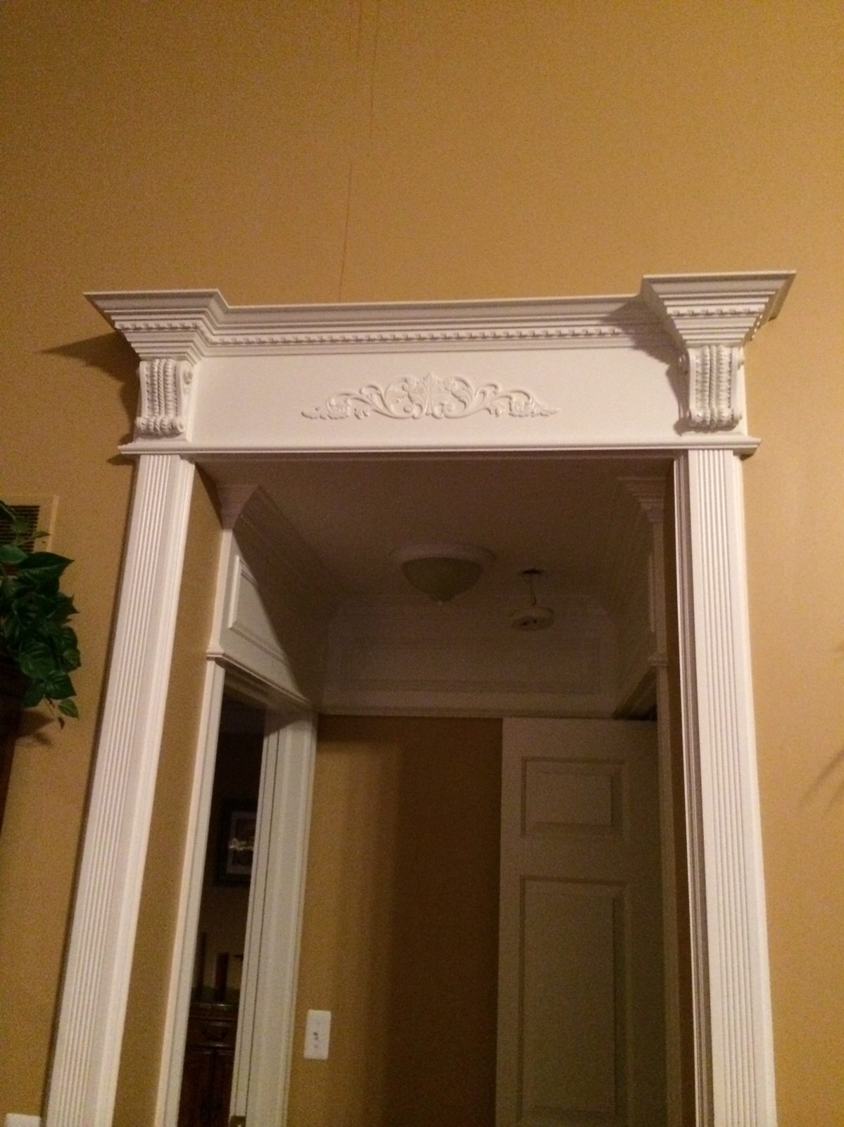 Painted door header with fluted pilasters, carved corbels, dentil crown and a carved applique across the top.